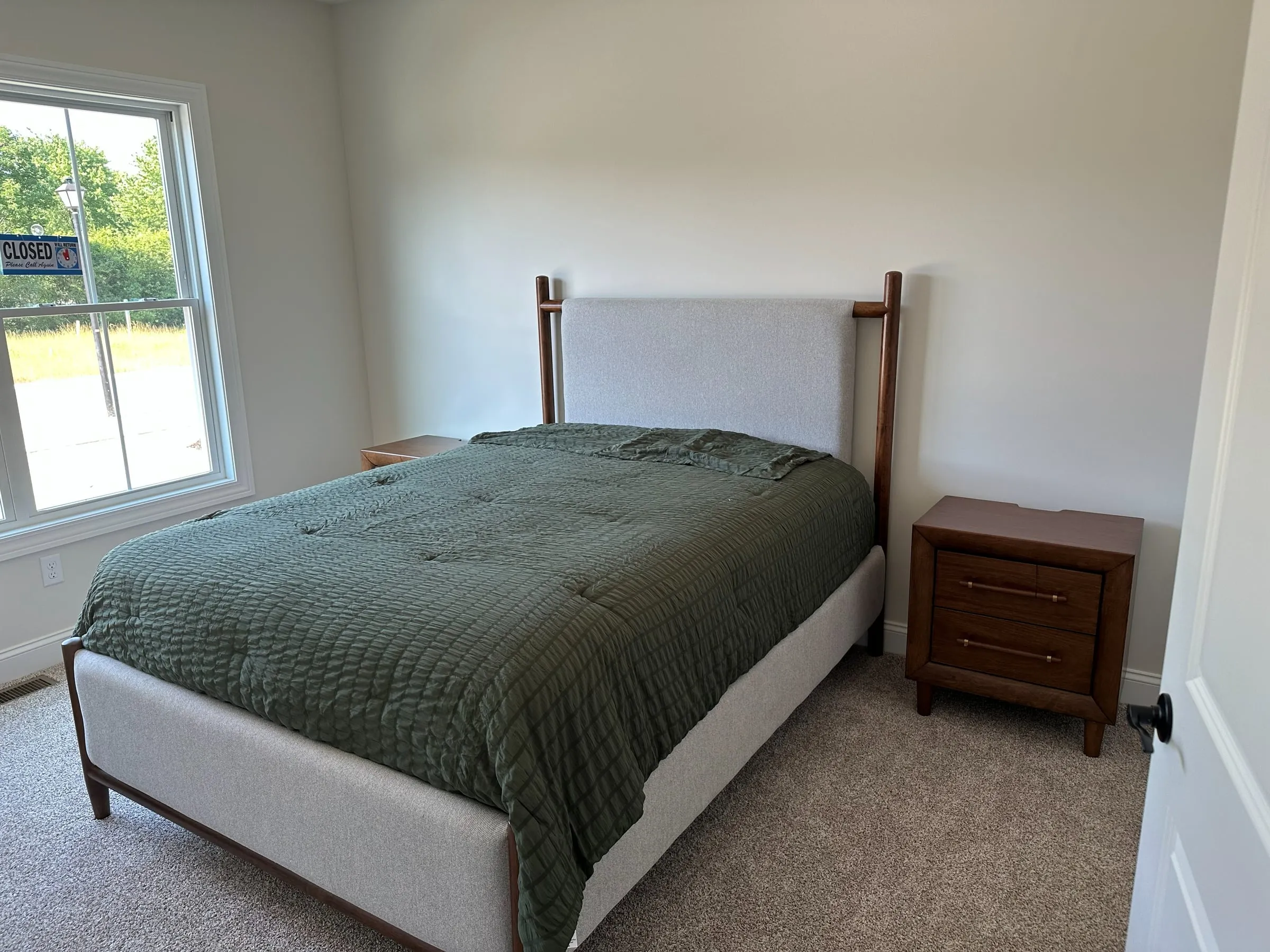 Model home guest bedroom with a green coverlet