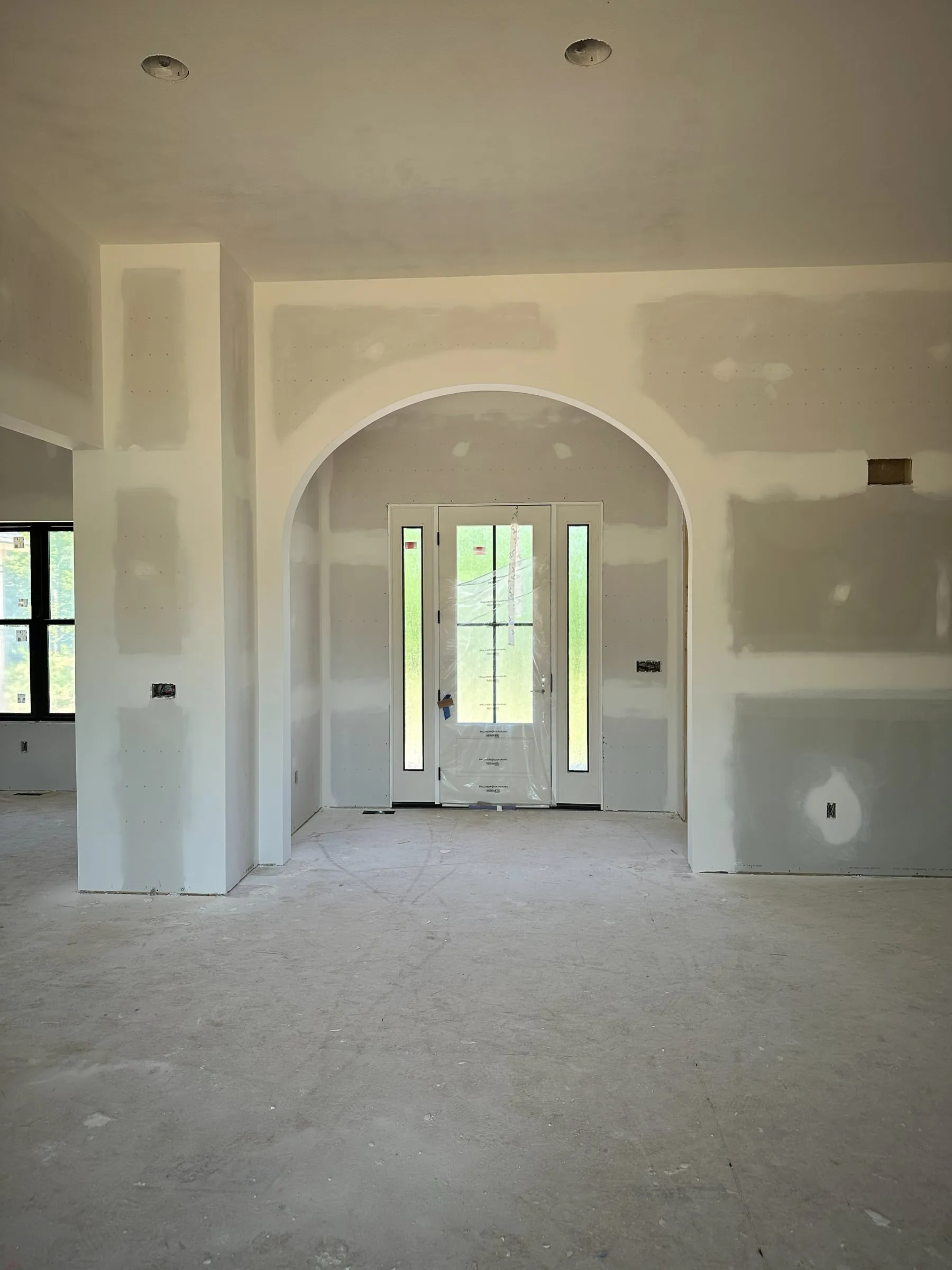 Drywalled entry with arched openings and the front door