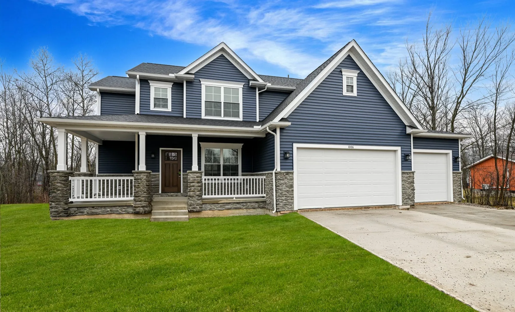 Two-story home with blue siding, stone, and a covered front porch