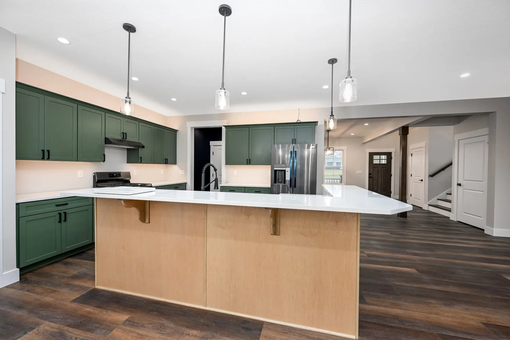Green cabinetry with a maple island and quartz counters