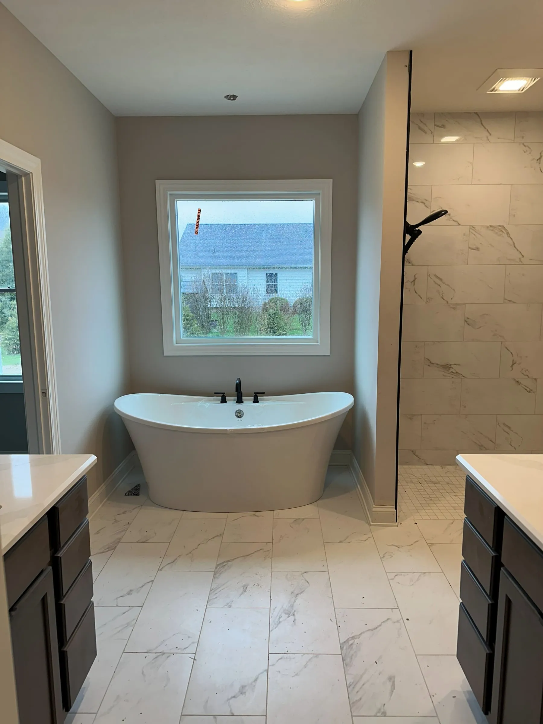 Owner's bath with a freestanding soaking tub and marble-tiled shower